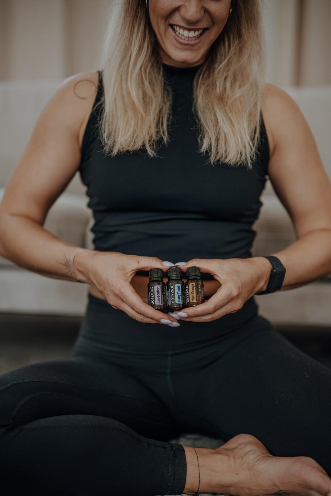Anki Strahl lacht und hält drei Fläschchen ätherische Öle von dōTERRA in den Händen
